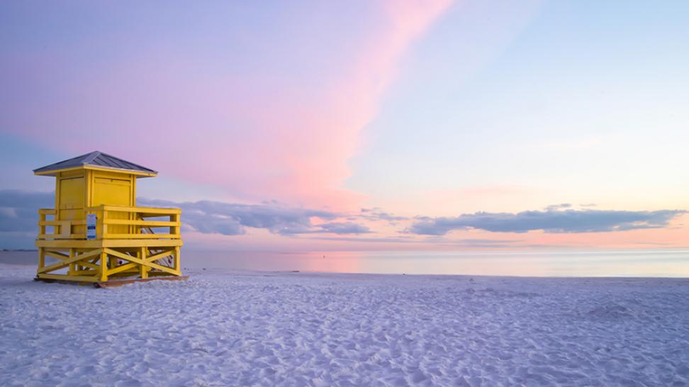 Pr pristine white quartz sand beach at Siesta Key with a colorful sunset sky and lifeguard stand